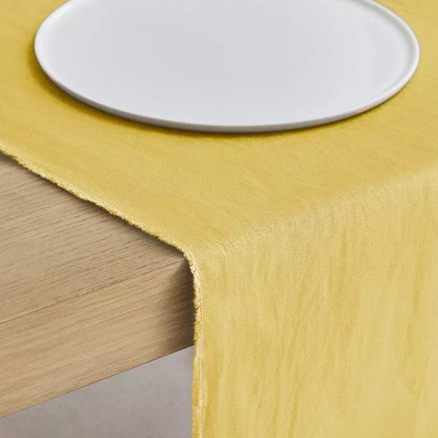 White porcelain plate on a mustard yellow linen table runner, Cadmium Yellow styling