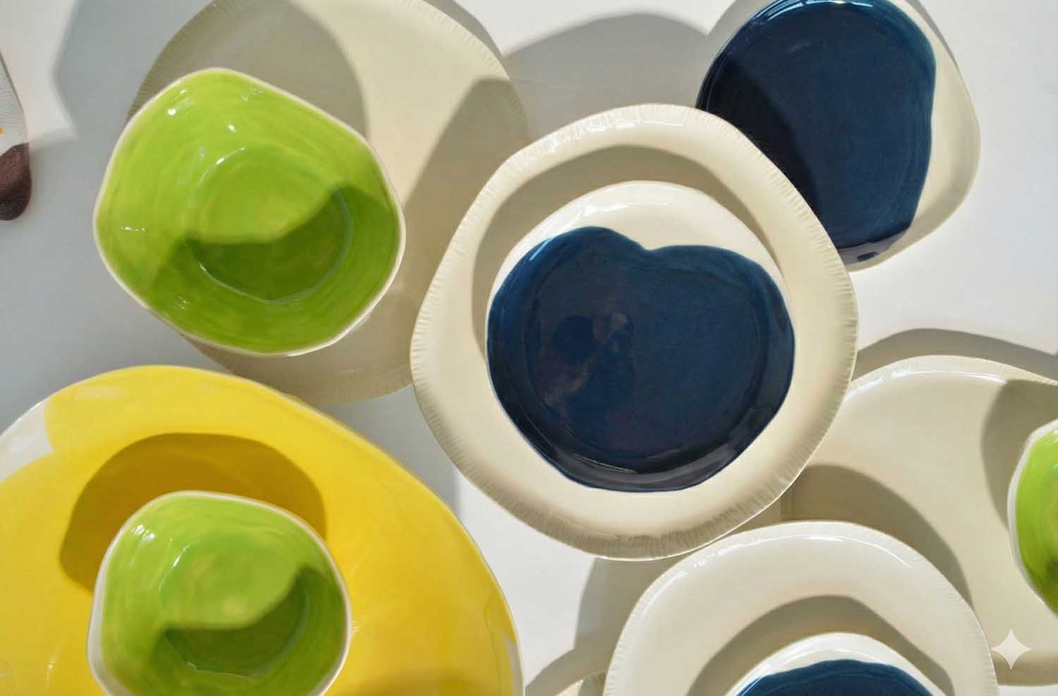 Close-up of lime green, Dark Denim and yellow handmade porcelain bowls from the 2026 palette