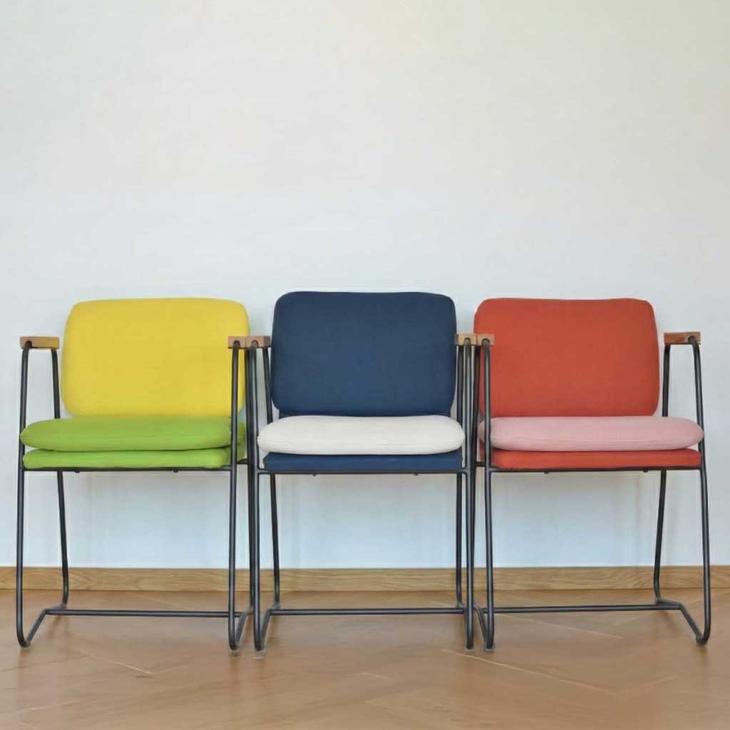 Three chairs in yellow and green, navy and coral upholstery reflecting the 2026 colour palette