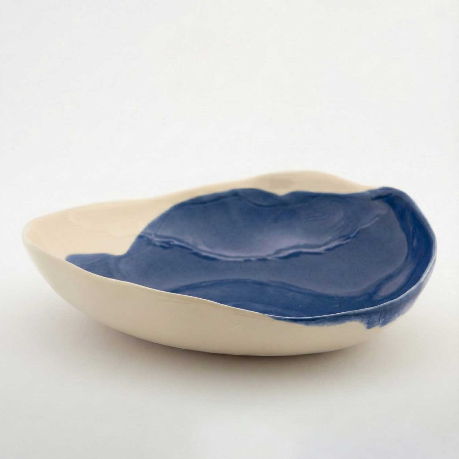 Organic porcelain serving bowl in ivory with a Dark Denim glaze pour inside