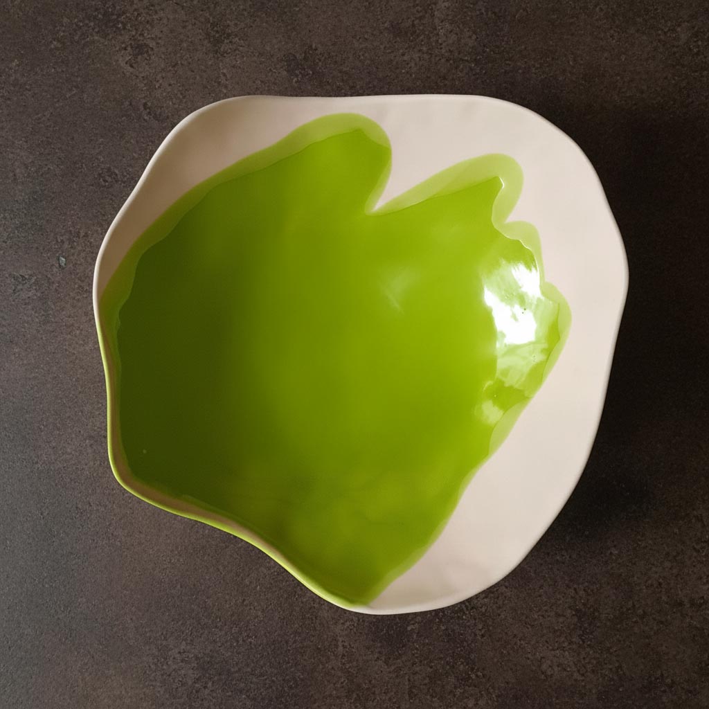 Overhead view of an organic porcelain serving platter in Electric Matcha glaze on dark stone