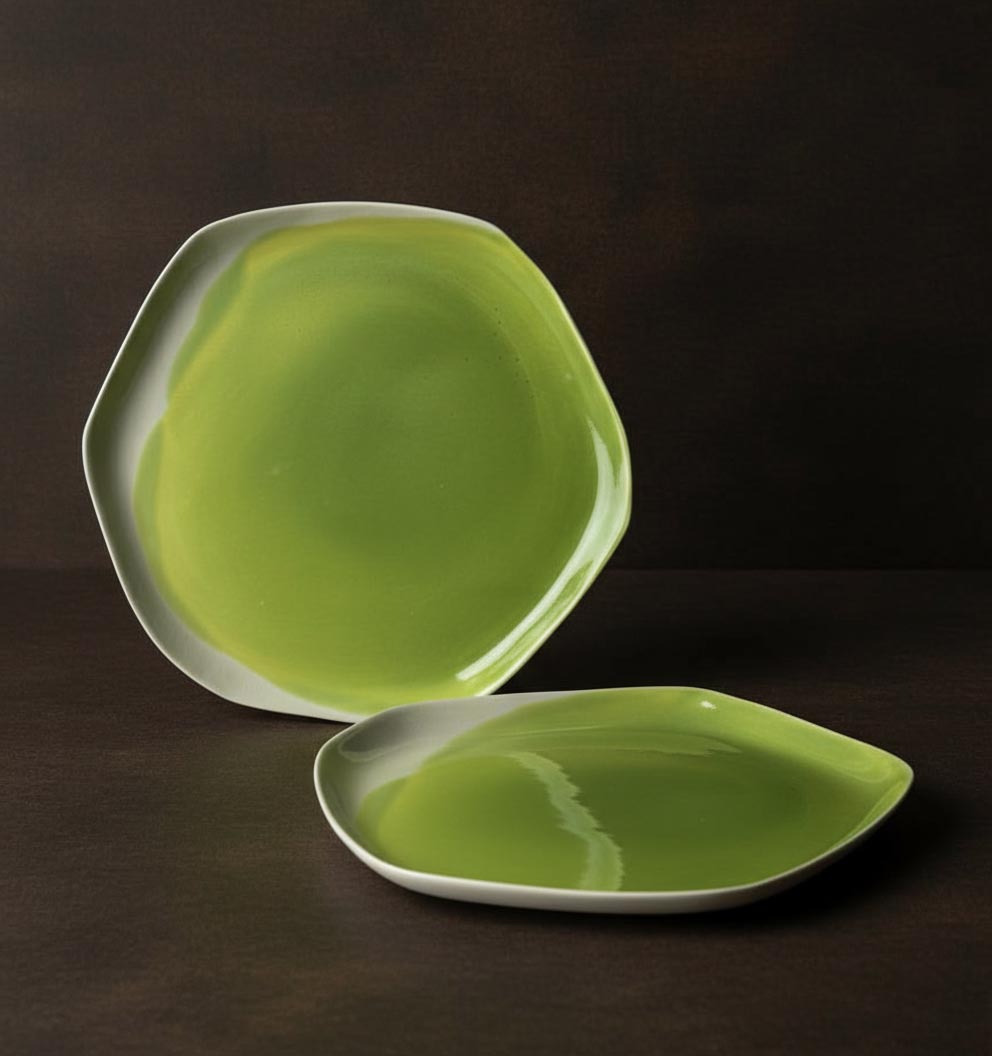 Two organic handmade porcelain plates in glossy Electric Matcha green glaze on dark background