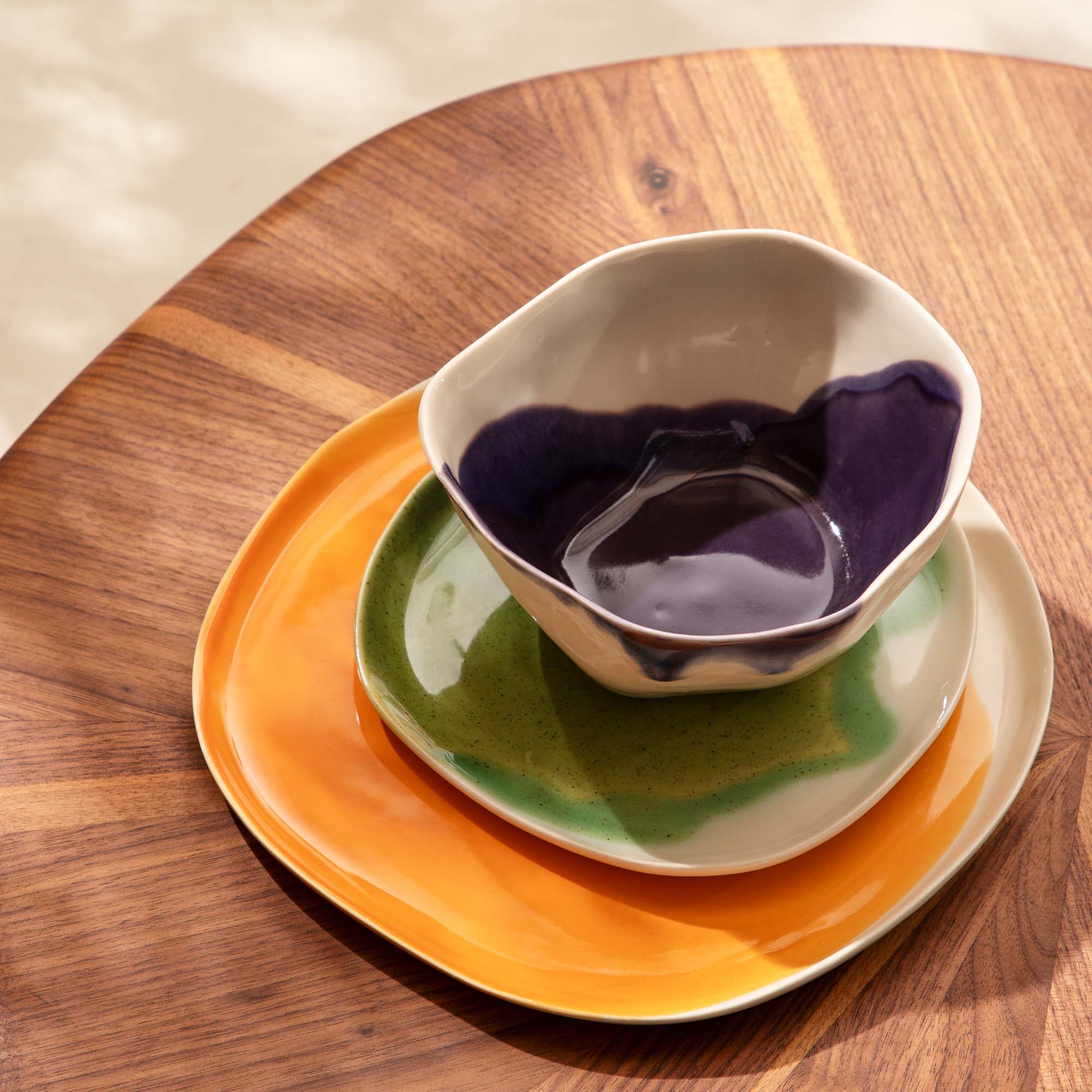 Personalised 3-piece dining set: orange plate, green plate and aubergine bowl on a walnut table