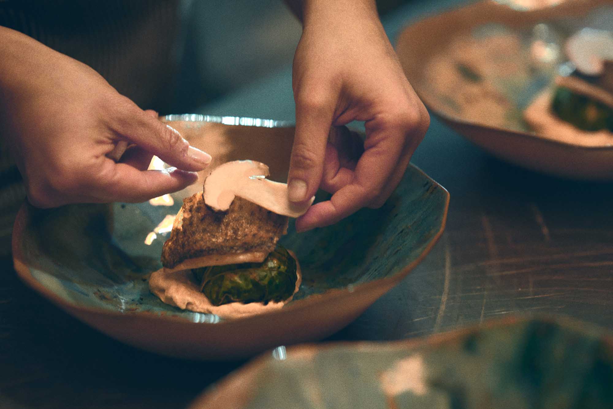 Chef's hands plating a dish on a Materia Mensa Episode 1 plate in turquoise reactive glaze
