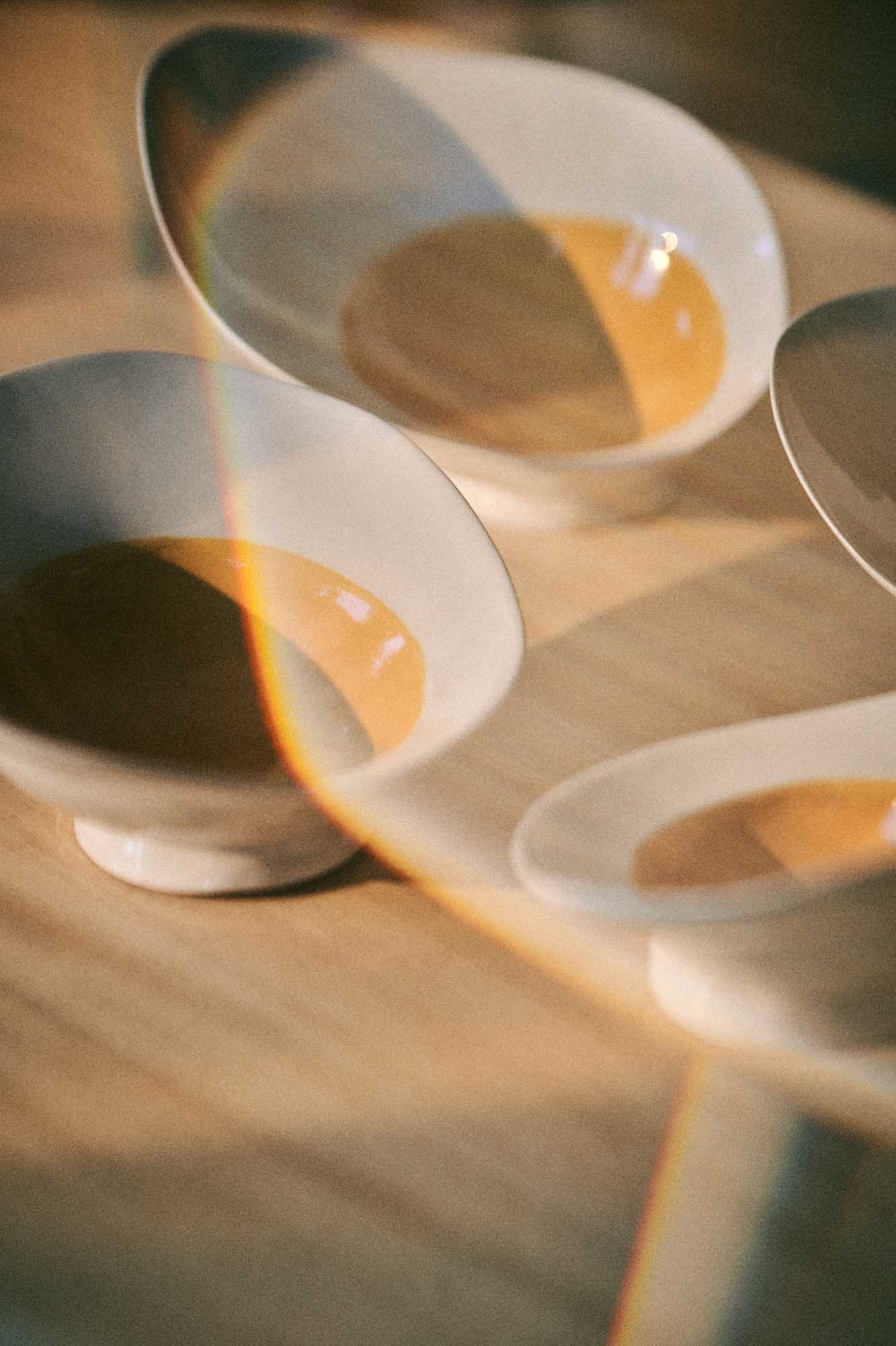 Egg-shaped white porcelain Ab Ovo bowls on pedestals with golden broth, Materia Mensa Episode 2