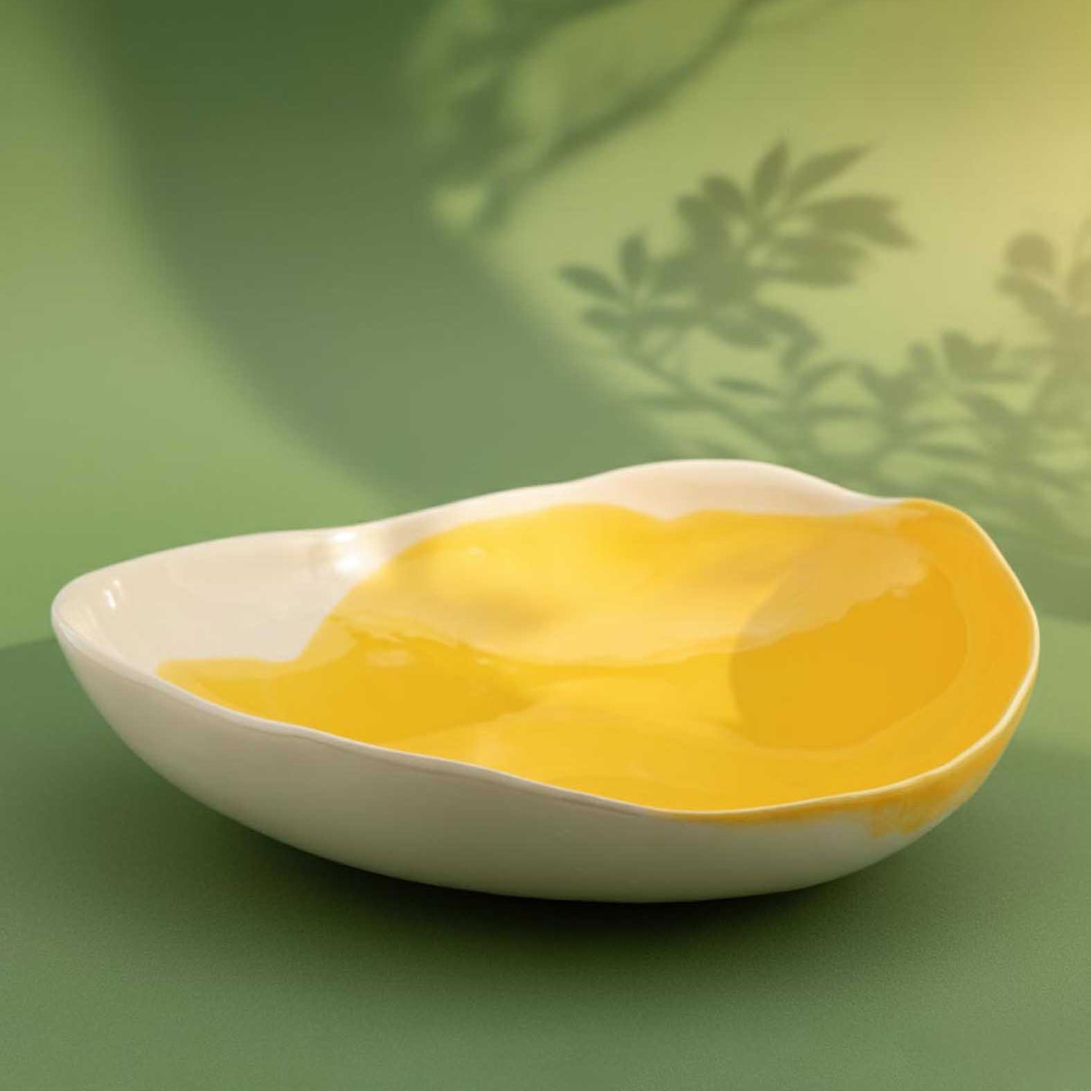 Large porcelain serving bowl in Cadmium Yellow glaze with a wavy organic rim on green
