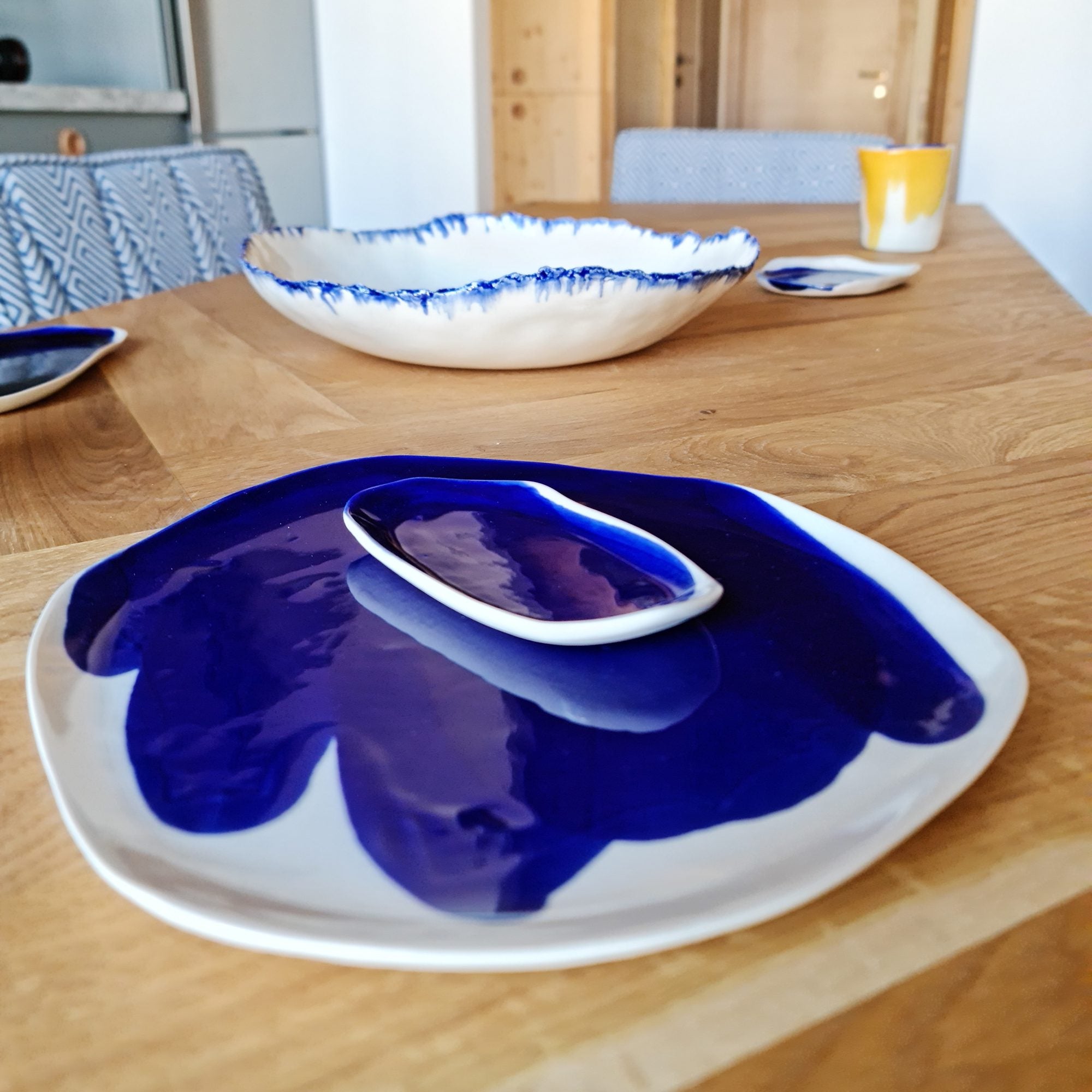 Royal Blue glazed porcelain plate, serving dish and bowl with blue brushed rims on a wooden table