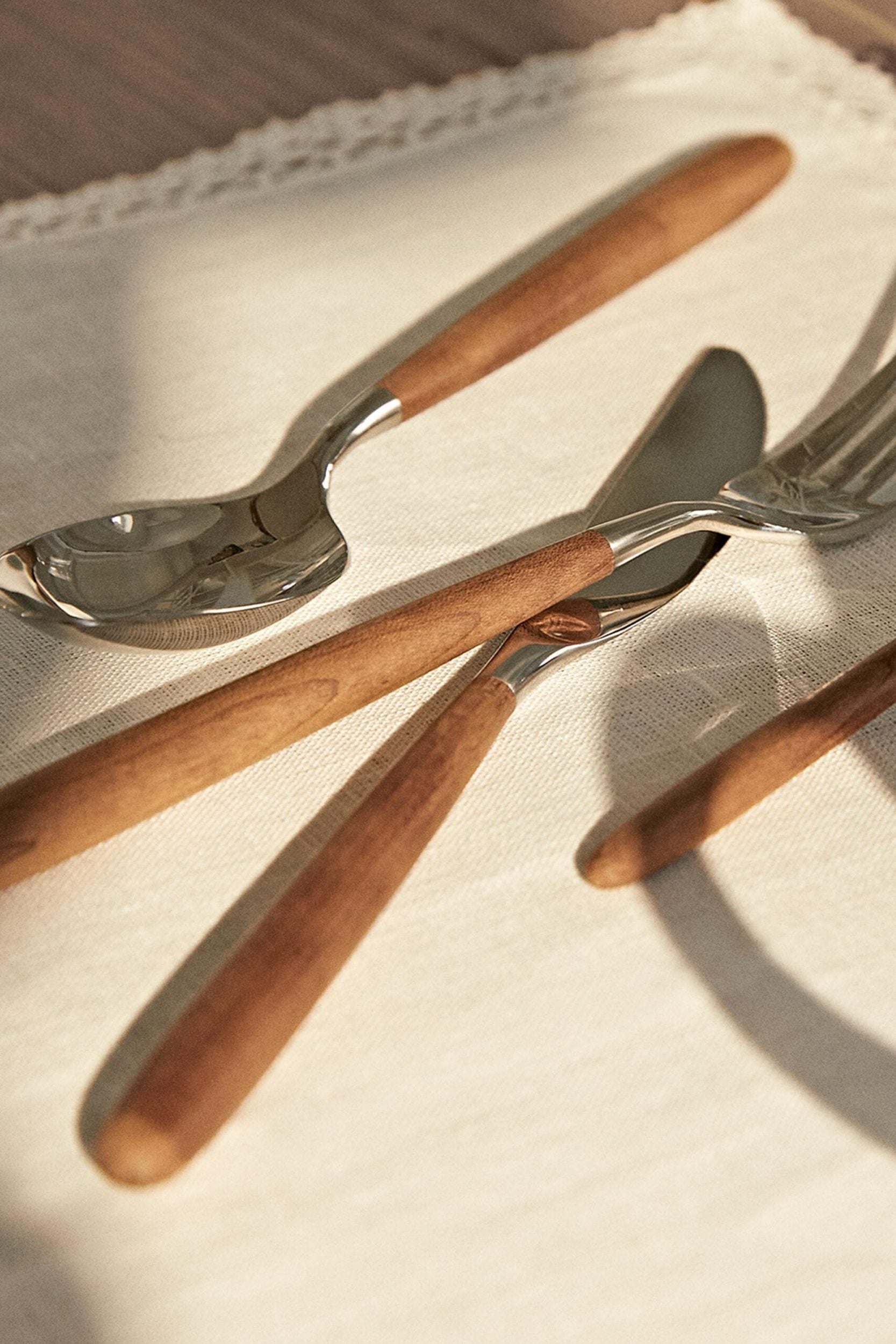 Wooden-handled cutlery on cream linen, styling for an autumn-coloured table setting